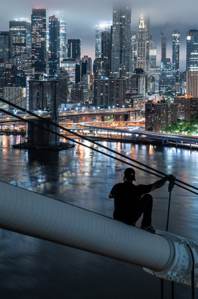L'homme est assis sur le pont en silhouette face à une ville